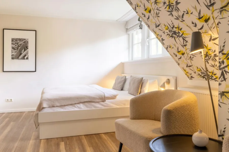 Helles Familienzimmer Petit im Boutique-Hotel STRANDHAUS Ahrenshoop auf dem Fischland-Darß-Zingst mit Doppelbett und gelb-grauer Blumentapete.