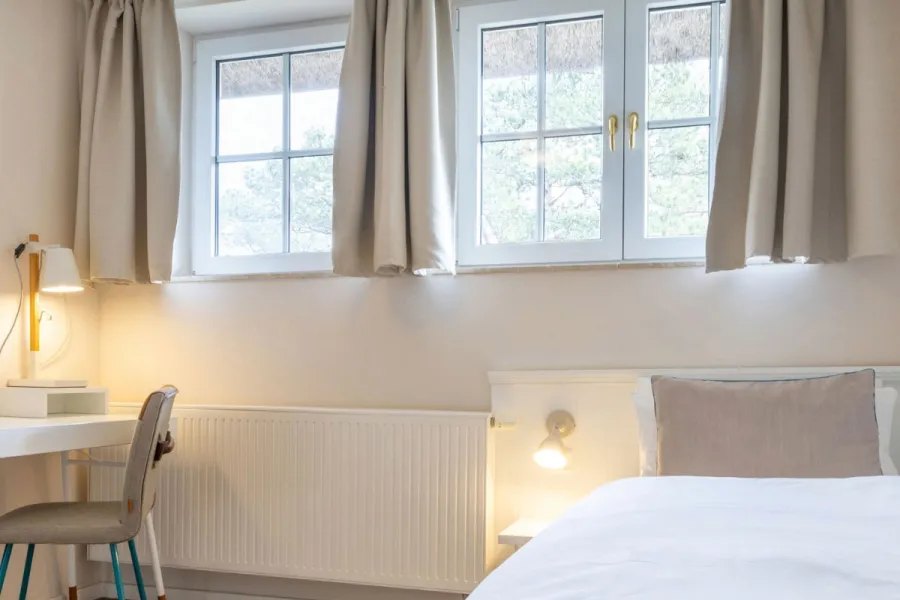 Helles Einzelzimmer im Boutique-Hotel STRANDHAUS Ahrenshoop auf dem Fischland-Darß-Zingst mit warmem Licht und Naturblick.