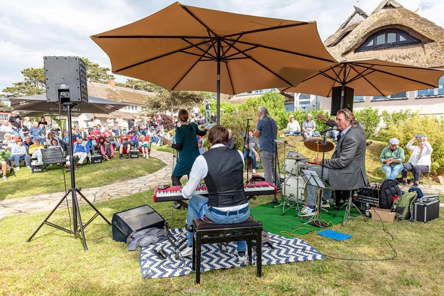 Liveband spielt bei einer Freiluftveranstaltung im Garten des STRANDHAUS Ahrenshoop vor zahlreichen Gästen.