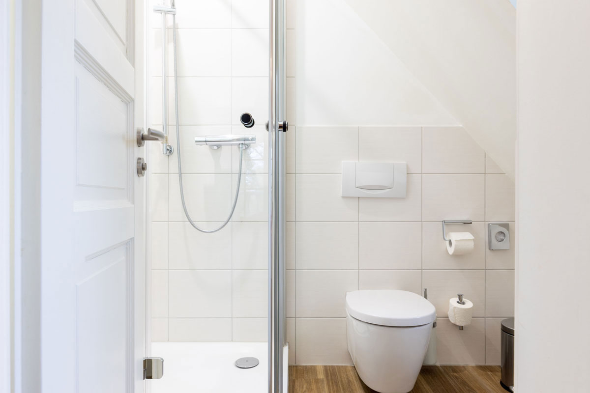 Kompaktes Bad im Doppelzimmer Petit des STRANDHAUS Ahrenshoop mit Glasdusche und WC unter der Dachschräge.