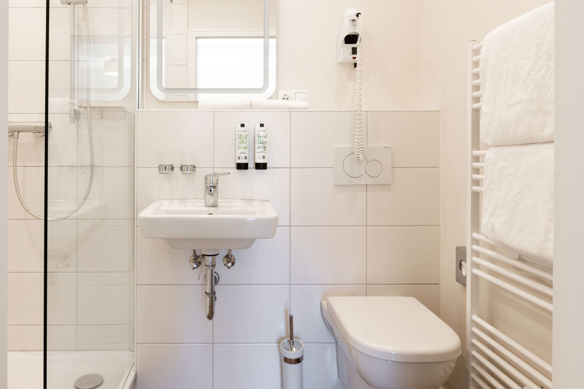 Badezimmer des Terrassenzimmers im STRANDHAUS Ahrenshoop mit Dusche, WC, Waschbecken und Handtuchheizkörper.
